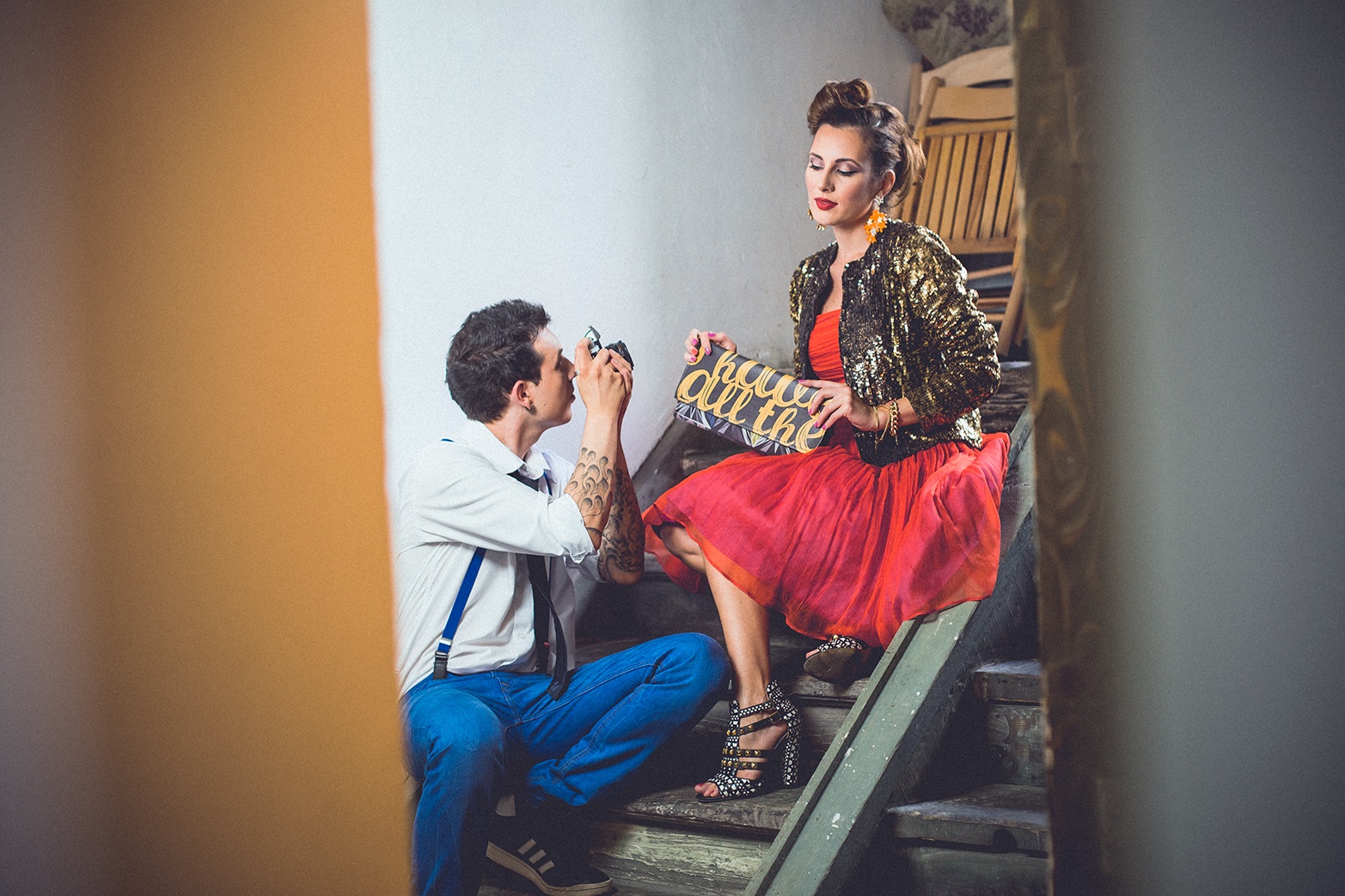 On fotografiše nju na stepenicama — zlatna jakna, crvena suknja, retro scena