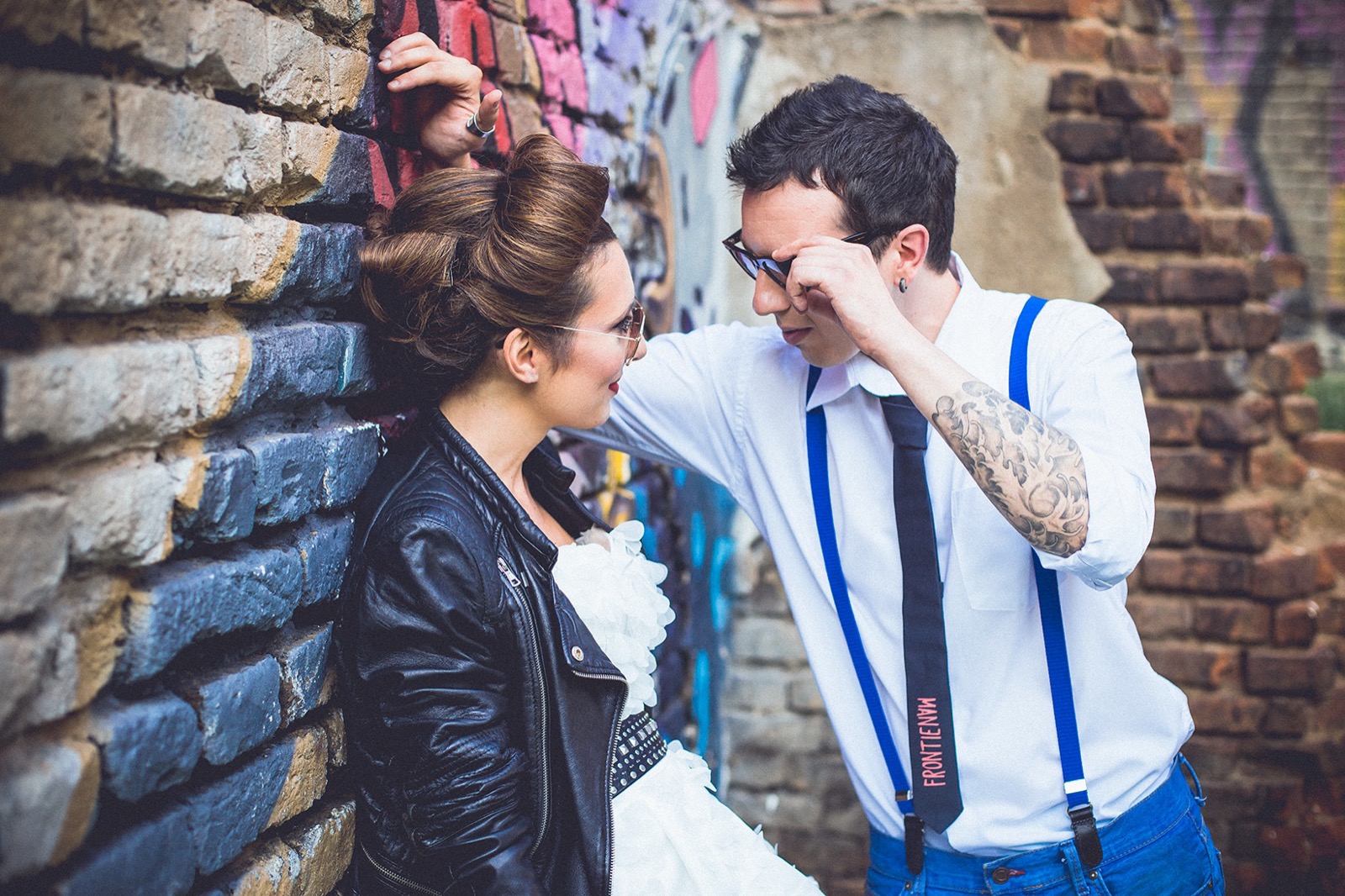 Par uz grafitni zid — on sa naočarima, ona u kožnoj jakni