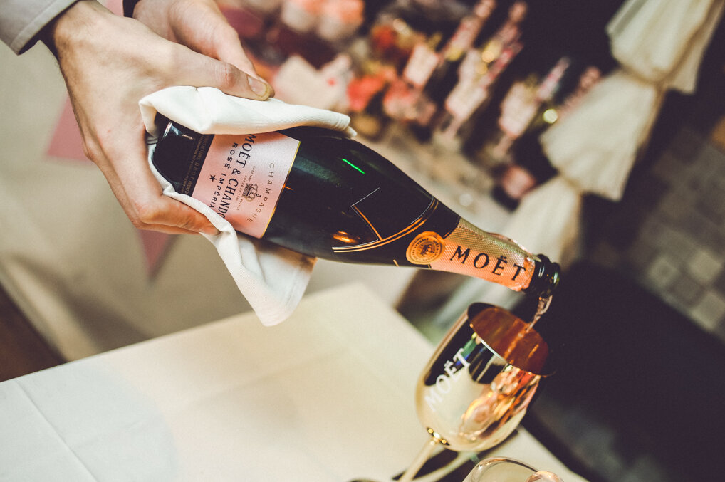 Moët Rosé Imperial se sipa u čašu — krupni plan šampanjca sa roze dekoracijom u pozadini