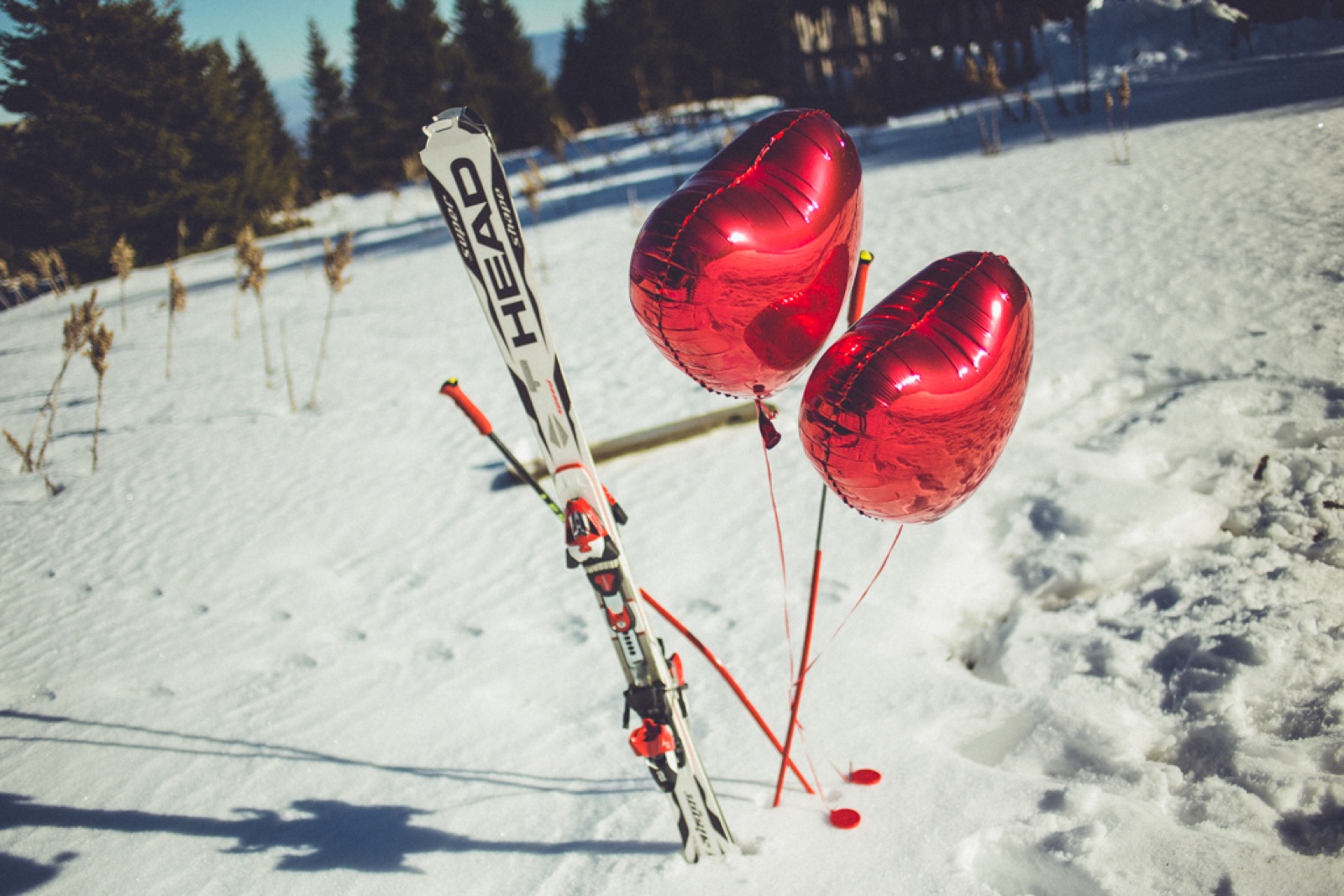 Skije sa crvenim balonima u obliku srca na snegu